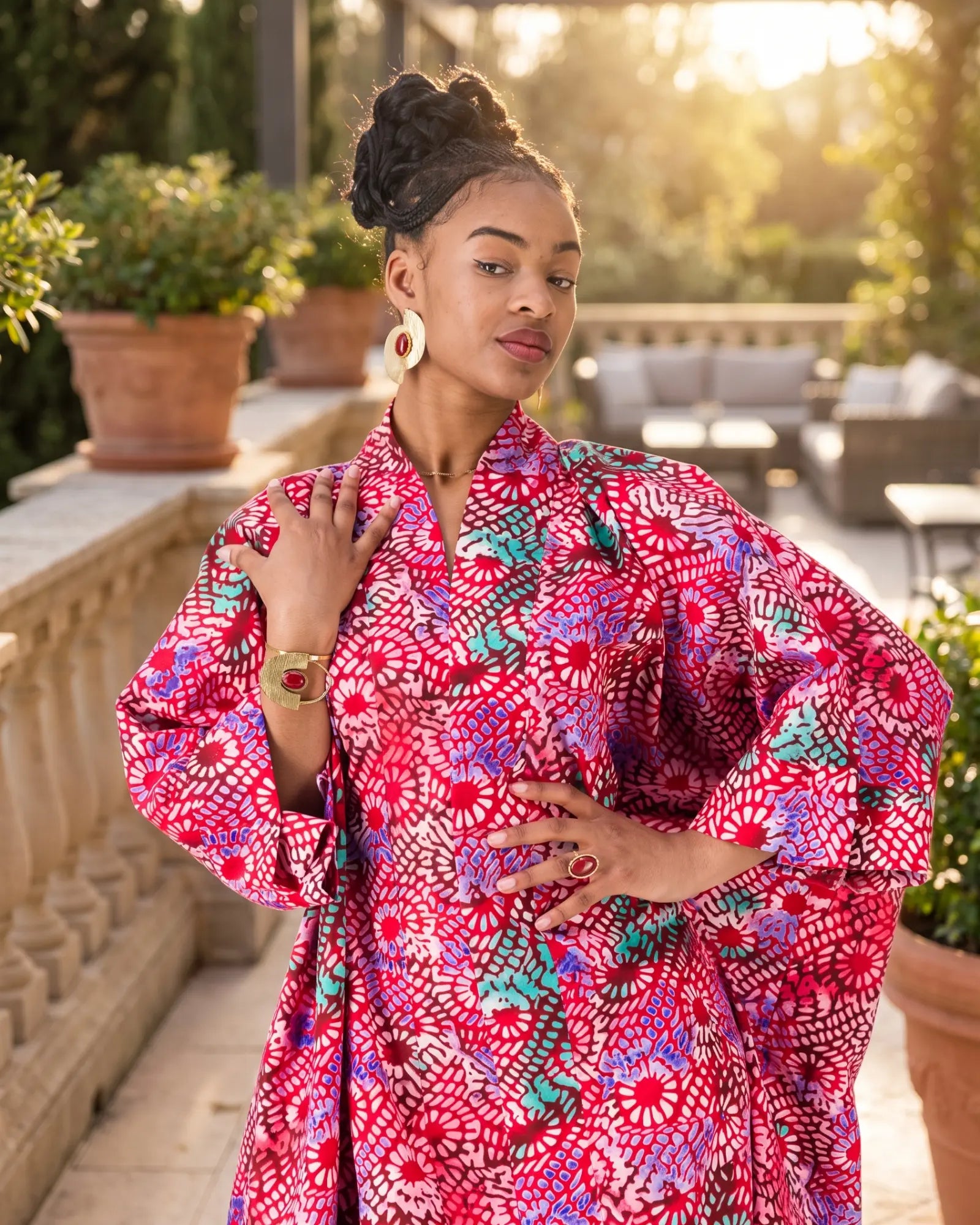 Femme portant des bijoux ethniques dorés avec une tenue africaine élégante sur une terrasse ensoleillée